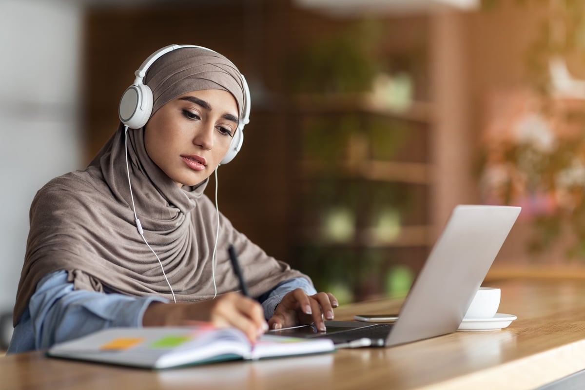 Student attending an online Quran class on a laptop with a headset