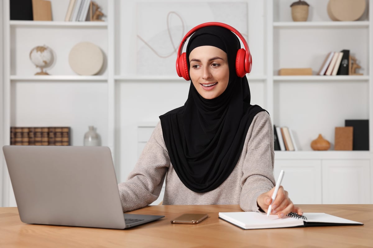 Student taking notes during an online Quran lesson